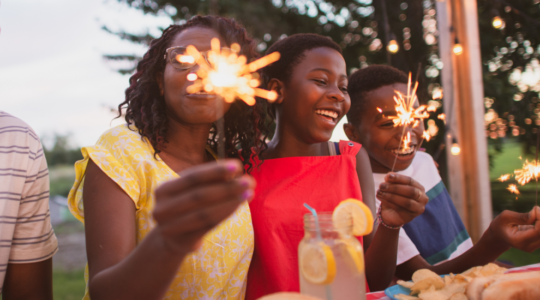 Family with sparklers follow firework safety tips 1100x550